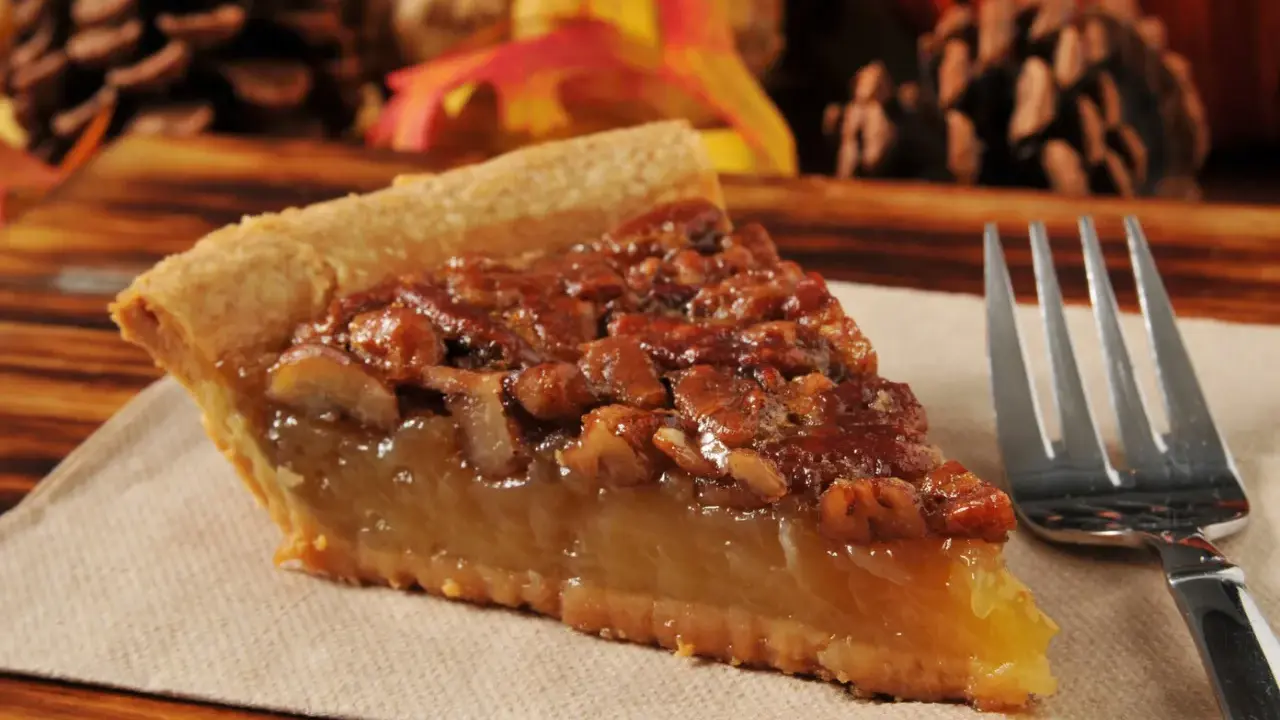 Kawałek pysznego, domowego pecan pie z orzechami i syropem, gotowy do zjedzenia.