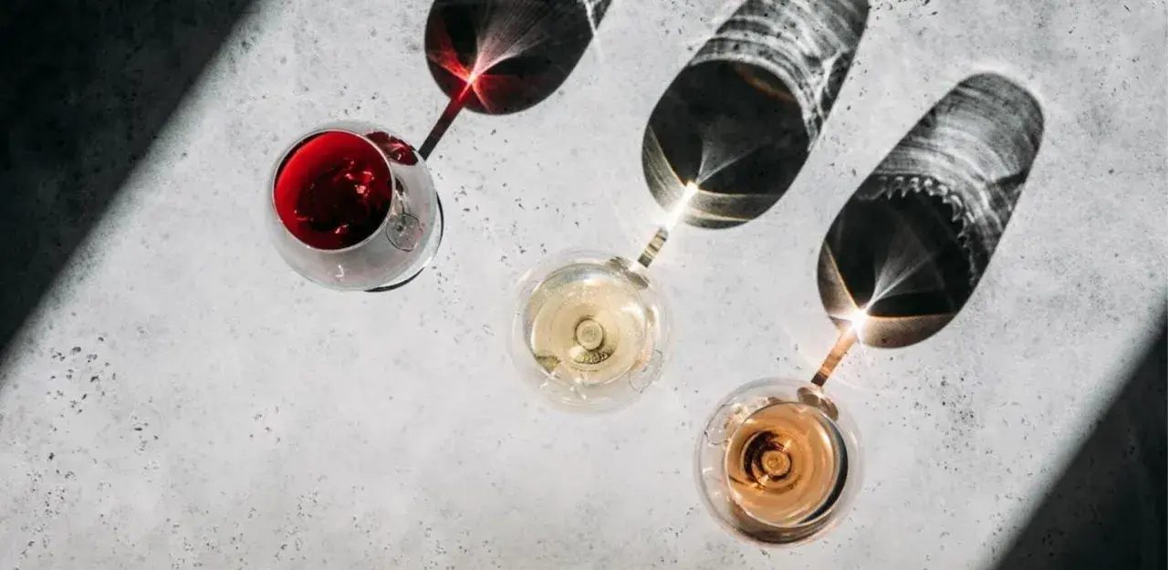Trzy kieliszki z winem: czerwonym, białym i różowym. Cienie rzucane przez kieliszki tworzą ciekawe wzory. Kto to sommelier? Ekspert od wina.