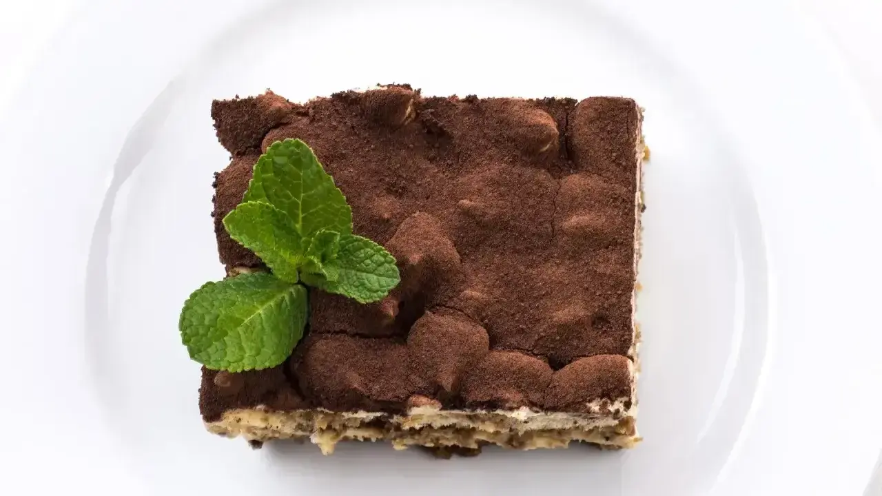 Pyszne tiramisu posypane kakao, z listkiem mięty. Zastanawiasz się, jaki alkohol do tiramisu wybrać?