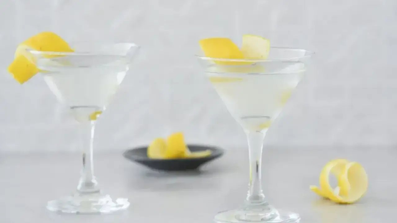 Dwa eleganckie kieliszki z orzeźwiającym martini, ozdobione skórką cytrynową. Idealne na letnie wieczory.