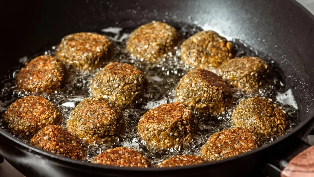 Falafelki smażą się na głębokim oleju w czarnej patelni. Idealny sposób, na czym najlepiej smażyć, by były chrupiące!