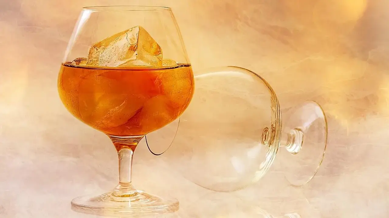 Szklanka z bursztynowym brandy i lodem, obok pusta, przewrócona kieliszek. To jest brandy, co to za napój?