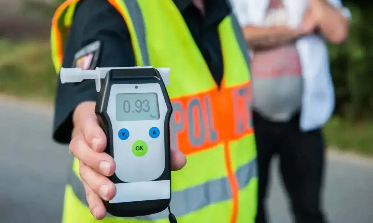 Policjant pokazuje alkomat z wynikiem 0.93 promila. Kierowca nie powinien wsiadać za kierownicę.