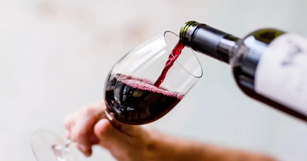 Czerwone wino nalewa się do kieliszka, tworząc idealną lampkę wina wieczorem.
