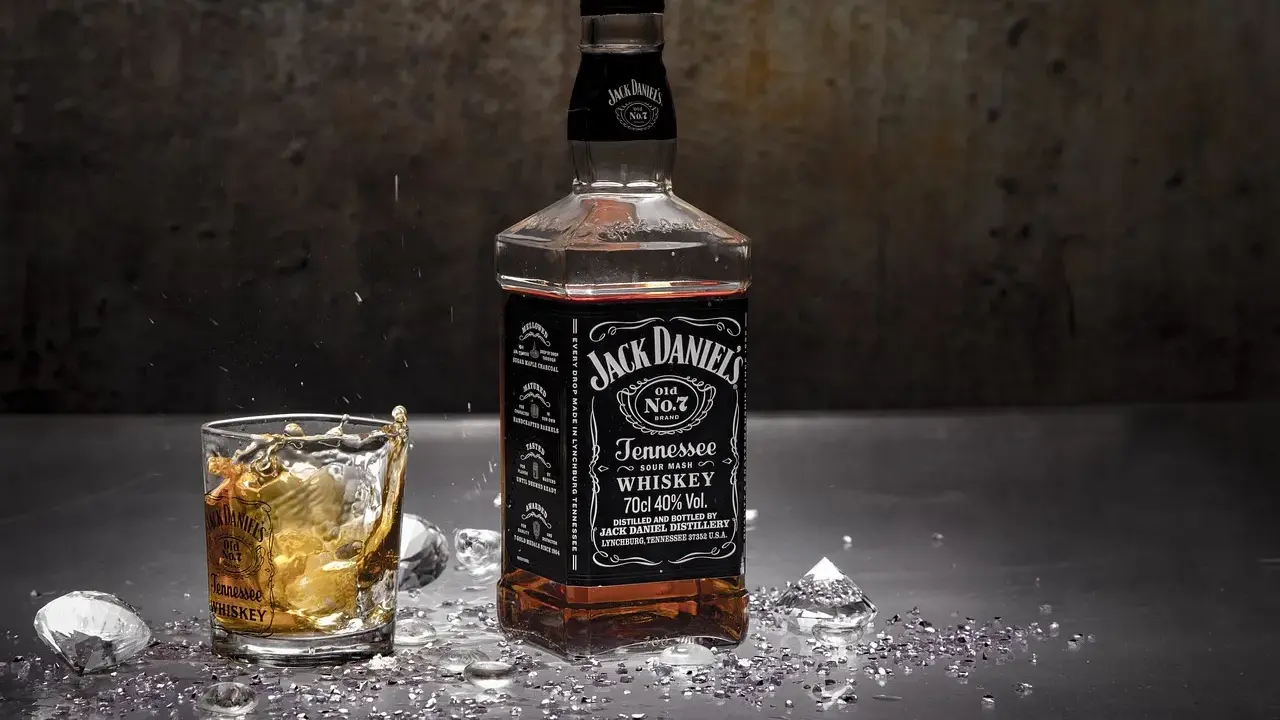 Butelka Jack Daniels i szklanka z whisky, z lodem i błyszczącymi drobinkami. Zastanawiasz się nad Jack Daniels kcal?