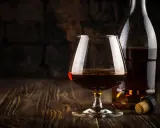 Kieliszek koniaku i butelka na drewnianym stole. Idealny do degustacji, zastanawiasz się, z czym pić koniak?