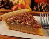 Kawałek pysznego, domowego pecan pie z orzechami i syropem, gotowy do zjedzenia.