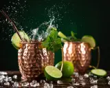 Orzeźwiający moscow mule drink z miętą i limonką, w miedzianych kubkach, z bryzgami wody i lodem.