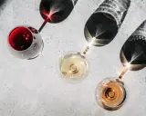 Trzy kieliszki z winem: czerwonym, białym i różowym. Cienie rzucane przez kieliszki tworzą ciekawe wzory. Kto to sommelier? Ekspert od wina.