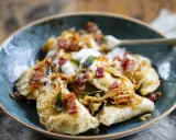 Pyszne pierogi z boczkiem i cebulką, polane śmietaną. Idealne, gdy zastanawiasz się, jak zrobić pierogi.