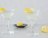 Dwa eleganckie kieliszki z orzeźwiającym martini, ozdobione skórką cytrynową. Idealne na letnie wieczory.