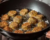 Falafelki smażą się na głębokim oleju w czarnej patelni. Idealny sposób, na czym najlepiej smażyć, by były chrupiące!