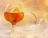 Szklanka z bursztynowym brandy i lodem, obok pusta, przewrócona kieliszek. To jest brandy, co to za napój?