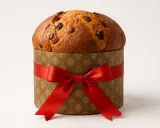 Panettone w ozdobnym pudełku z czerwoną wstążką. Idealny na święta, zachęca do wypróbowania panettone przepis.