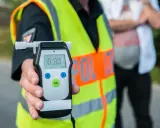 Policjant pokazuje alkomat z wynikiem 0.93 promila. Kierowca nie powinien wsiadać za kierownicę.