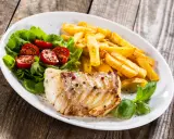 Pieczona ryba z frytkami i sałatką. Idealne jakie przyprawy do ryby pieczonej? Sól, pieprz, zioła.
