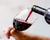 Czerwone wino nalewa się do kieliszka, tworząc idealną lampkę wina wieczorem.
