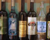 Rząd butelek z napisem "Absynt co to". Widać różne marki, m.in. Clandestine, Eichelberger, Duplais, La Bonne Mere, Butterfly Absinthe.