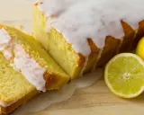 Pyszne, wilgotne ciasto cytrynowe z lukrem, obok świeże cytryny. Idealne na popołudniową herbatkę.