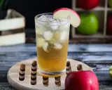 Orzeźwiający drink: whisky z sokiem jabłkowym, lodem i plasterkiem jabłka. Idealny na letnie popołudnie.