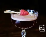 Elegancki koktajl Clover Club z maliną na patyczku, serwowany w kieliszku z logo MOJ BAR.