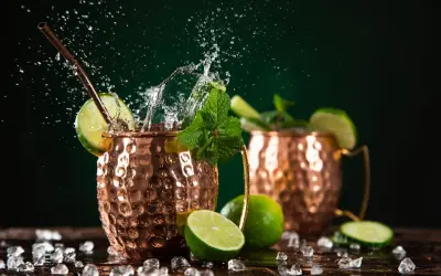 Orzeźwiający moscow mule drink z miętą i limonką, w miedzianych kubkach, z bryzgami wody i lodem.