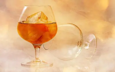 Szklanka z bursztynowym brandy i lodem, obok pusta, przewrócona kieliszek. To jest brandy, co to za napój?