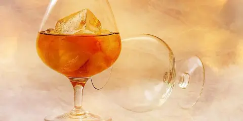 Szklanka z bursztynowym brandy i lodem, obok pusta, przewrócona kieliszek. To jest brandy, co to za napój?