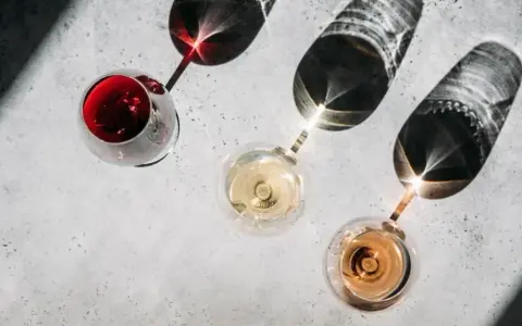 Trzy kieliszki z winem: czerwonym, białym i różowym. Cienie rzucane przez kieliszki tworzą ciekawe wzory. Kto to sommelier? Ekspert od wina.