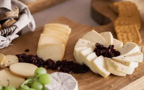 Deska serów z winogronami, suszoną żurawiną i pieczywem. Idealny sposób, jak podawać sery na przyjęciu.