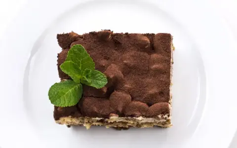 Pyszne tiramisu posypane kakao, z listkiem mięty. Zastanawiasz się, jaki alkohol do tiramisu wybrać?