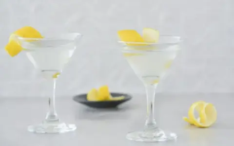 Dwa eleganckie kieliszki z orzeźwiającym martini, ozdobione skórką cytrynową. Idealne na letnie wieczory.
