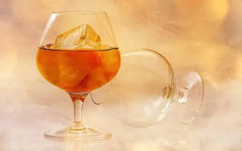 Szklanka z bursztynowym brandy i lodem, obok pusta, przewrócona kieliszek. To jest brandy, co to za napój?