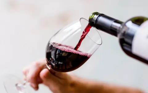 Czerwone wino nalewa się do kieliszka, tworząc idealną lampkę wina wieczorem.