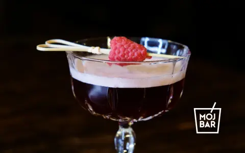 Elegancki koktajl Clover Club z maliną na patyczku, serwowany w kieliszku z logo MOJ BAR.