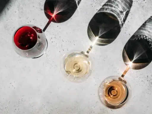 Trzy kieliszki z winem: czerwonym, białym i różowym. Cienie rzucane przez kieliszki tworzą ciekawe wzory. Kto to sommelier? Ekspert od wina.