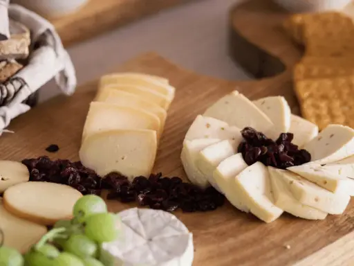 Deska serów z winogronami, suszoną żurawiną i pieczywem. Idealny sposób, jak podawać sery na przyjęciu.