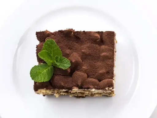 Pyszne tiramisu posypane kakao, z listkiem mięty. Zastanawiasz się, jaki alkohol do tiramisu wybrać?