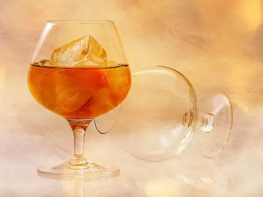 Szklanka z bursztynowym brandy i lodem, obok pusta, przewrócona kieliszek. To jest brandy, co to za napój?