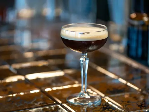 Idealny espresso martini przepis na orzeźwiający drink. Ciemny napój z pianką w kieliszku.