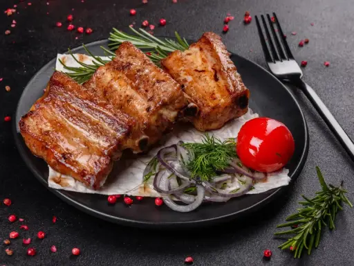 Soczysta żeberka jak piec, podane z pomidorkiem, cebulą i rozmarynem.