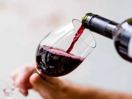 Czerwone wino nalewa się do kieliszka, tworząc idealną lampkę wina wieczorem.