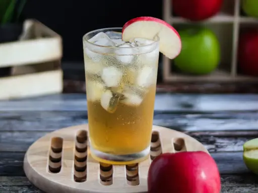 Orzeźwiający drink: whisky z sokiem jabłkowym, lodem i plasterkiem jabłka. Idealny na letnie popołudnie.