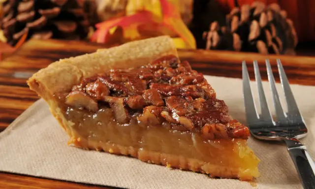 Kawałek pysznego, domowego pecan pie z orzechami i syropem, gotowy do zjedzenia.
