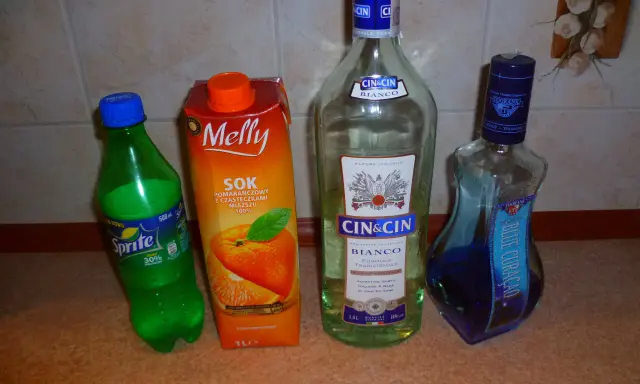 Składniki na drinki z Żabki: Sprite, sok pomarańczowy, Cin&Cin Bianco i Blue Curacao.