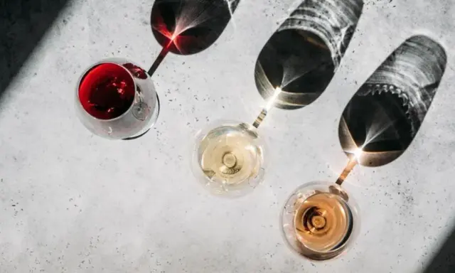 Trzy kieliszki z winem: czerwonym, białym i różowym. Cienie rzucane przez kieliszki tworzą ciekawe wzory. Kto to sommelier? Ekspert od wina.