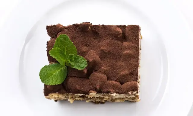 Pyszne tiramisu posypane kakao, z listkiem mięty. Zastanawiasz się, jaki alkohol do tiramisu wybrać?