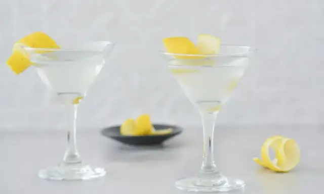 Dwa eleganckie kieliszki z orzeźwiającym martini, ozdobione skórką cytrynową. Idealne na letnie wieczory.