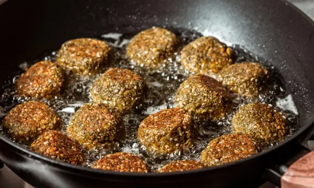 Falafelki smażą się na głębokim oleju w czarnej patelni. Idealny sposób, na czym najlepiej smażyć, by były chrupiące!