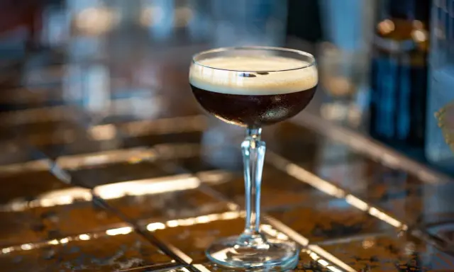 Idealny espresso martini przepis na orzeźwiający drink. Ciemny napój z pianką w kieliszku.